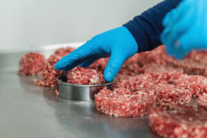 Hand of a chef preparing burgers, close up